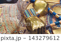 Tutankhamun's golden burial mask featuring blue inlays, a headdress, and arms crossed over the chest holding a crook and flail 143279612