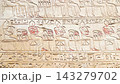Ancient Egyptian hieroglyphic wall featuring densely carved horizontal rows of detailed stone inscriptions 143279702