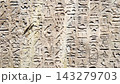 Ancient Egyptian hieroglyphic wall featuring densely carved horizontal rows of detailed stone inscriptions 143279703