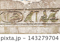 Ancient Egyptian hieroglyphic wall featuring densely carved horizontal rows of detailed stone inscriptions 143279704
