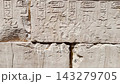 Ancient Egyptian hieroglyphic wall featuring densely carved horizontal rows of detailed stone inscriptions 143279705