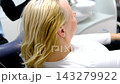 Dental implant crown placement using cheek retractor implant screwdriver and saliva ejector followed by patient smiling at beautiful treatment result in mirror 143279922