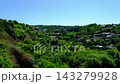Green Hillside Neighborhood with Houses Surrounded by Dense Trees and Lush Summer Vegetation in Kamianets Podilskyi Ukraine 143279928
