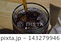 Pouring cola into glass filled with ice cubes on wooden table in dark restaurant atmosphere 143279946