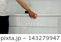 Man in white shirt and dark trousers closing drawer of modern white cabinet in clean medical office creating organized workspace close up video 143279947