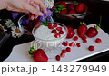 Female hand decorating yogurt with fresh strawberries and mint leaves on white plate, healthy breakfast with natural ingredients, balanced nutrition and clean eating lifestyle 143279949