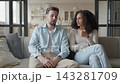 Young Couple Talking Together While Sitting On Sofa At Home Living Room 143281709
