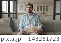 Relaxed Man Holding Remote And Popcorn While Watching Television At Home 143281723