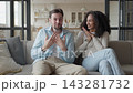 Happy Couple Talking On Sofa While Woman Reacts To Good News At Home 143281732