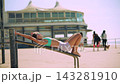 Seaside scene with woman reaching skyward in casual pose 143281910