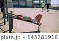 Fitness enthusiast performing abdominal exercises beside seaside promenade 143281916