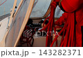 A sailor in a red foul-weather jacket coils a rigging line in the yacht cockpit 143282371