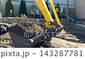 Bucket tracked excavator levels the ground in backyard house. Mini excavator scoops up soil, construction work supervised engineer. Earthworks being carried out using excavator. Building, Earthmoving 143287781