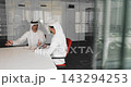 Two Arab businessmen dressed in kanduras communicating at conference table 143294253