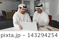 Two Arab businessmen clasping hands in strong, celebratory handshake gesture 143294254