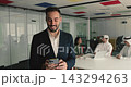 Focused Hispanic businessman dressed in suit using smartphone 143294263