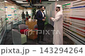 Arabic man dressed in white thobe talks with Hispanic colleague 143294264
