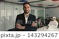Confident smiling Hispanic businessman stands in modern boardroom 143294267