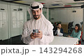 Arabic man in traditional white kandura using smartphone 143294268