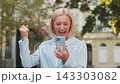 Mature Caucasian businesswoman CEO celebrating good news on smartphone standing on city street 143303082
