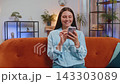 Happy young woman text messaging on smartphone watching online social media video movie at home 143303089