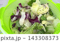Fresh mixed iceberg and radicchio salad leaves inside plastic salad spinner on kitchen table for washing drying and preserving greenery concept. 143308373