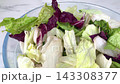 Fresh mixed iceberg and radicchio salad leaves inside clear glass bowl placed on marble table background for healthy nutrition concept on kitchen. 143308377
