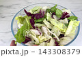 Fresh mixed iceberg and radicchio salad leaves inside clear glass bowl placed on marble table background for healthy nutrition concept on kitchen. 143308379