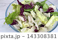 Fresh mixed iceberg and radicchio salad leaves inside clear glass bowl placed on marble table background for healthy nutrition concept on kitchen. 143308381