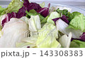 Fresh mixed iceberg and radicchio salad leaves inside clear glass bowl placed on marble table background for healthy nutrition concept on kitchen. 143308383