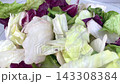 Fresh mixed iceberg and radicchio salad leaves inside clear glass bowl placed on marble table background for healthy nutrition concept on kitchen. 143308384