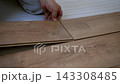 Close-up of man kneeling on the floor and connecting two laminate planks during home renovation process. 143308485