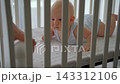 Close-up of father placing baby monitor camera in front of five-month-old son in crib. Infant care. 143312106