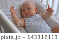 Close-up of three-month-old baby boy actively moving hands and legs in crib. 143312113