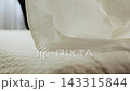 In a bright bedroom, a man lifts a sheet up with his hands and spreads it onto the surface of the double bed mattress. Slow motion. In focus extreme close up shot  143315844