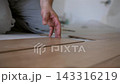 Worker aligning and clicking laminate floor panels together. The master uses a brush to remove dust from the joints of the laminate plate 143316219