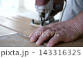 Man uses jigsaw to trim laminate plank for precise fitting around room corners and wall angles during floor installation. 143316325