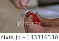 Close-up of plumber wrapping sealing thread around red hot water pipe plug to prevent leakage during plumbing installation. 143316330