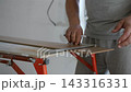 Worker using square ruler to check right angle on laminate panel before trimming. Detailed flooring preparation and carpentry work. 143316331