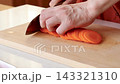 A woman's hands as she finely chops carrots. 143321310