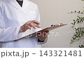 A person in a white coat checking the contents of a document. 143321481