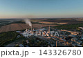 Cement plant rotary kiln lines and exhaust stacks beside farmland in a drone aerial view. Cement manufacturing, clinker production infrastructure and industrial process heat 143326780
