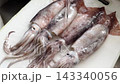 Freshly caught squid being washed under running water before cooking. 143340056