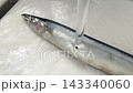 Preparing the saury by washing it under running water before cooking. 143340060