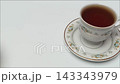 Hand Placing Plate of Fried Bread Next to Hot Black Coffee Cup 143343979