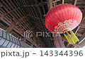 Large Red Chinese Lantern Hanging Under Intricate Wooden Ceiling in Traditional Temple Interior During Festival Decoration 143344396