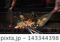 Close-up Action Shot of Sizzling Stir-Fried Vegetables and Meat on a Hot Griddle. 143344398