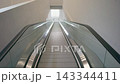 Minimalist Perspective of a Long Symmetrical Escalator Leading into a Bright White Corridor. 143344411