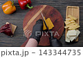 Slicing cheddar cheese on wooden board with ingredients top view 143344735