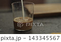 Pour milk into glass with shot of espresso 143345567